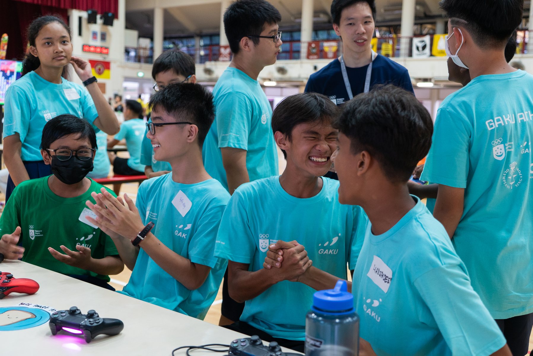 GAKU students in branded teal shirts laughing together at a Singapore games session